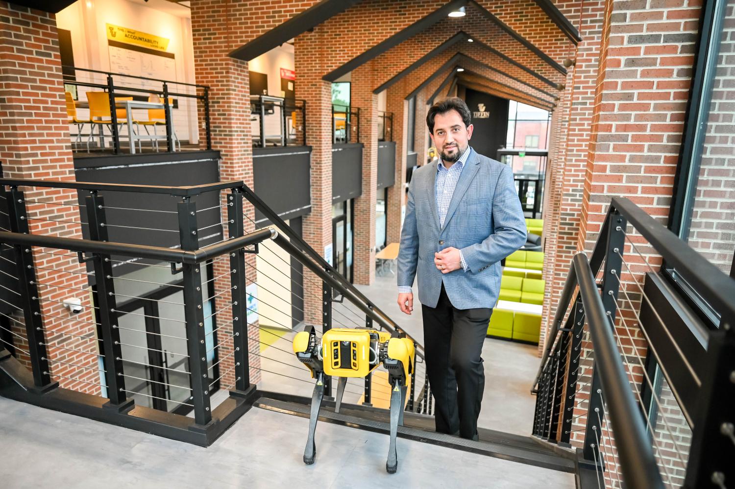 Dr. Anas H. Blasi stands with Spot, a dynamic highly mobile robot made Boston Dynamics, Inc.